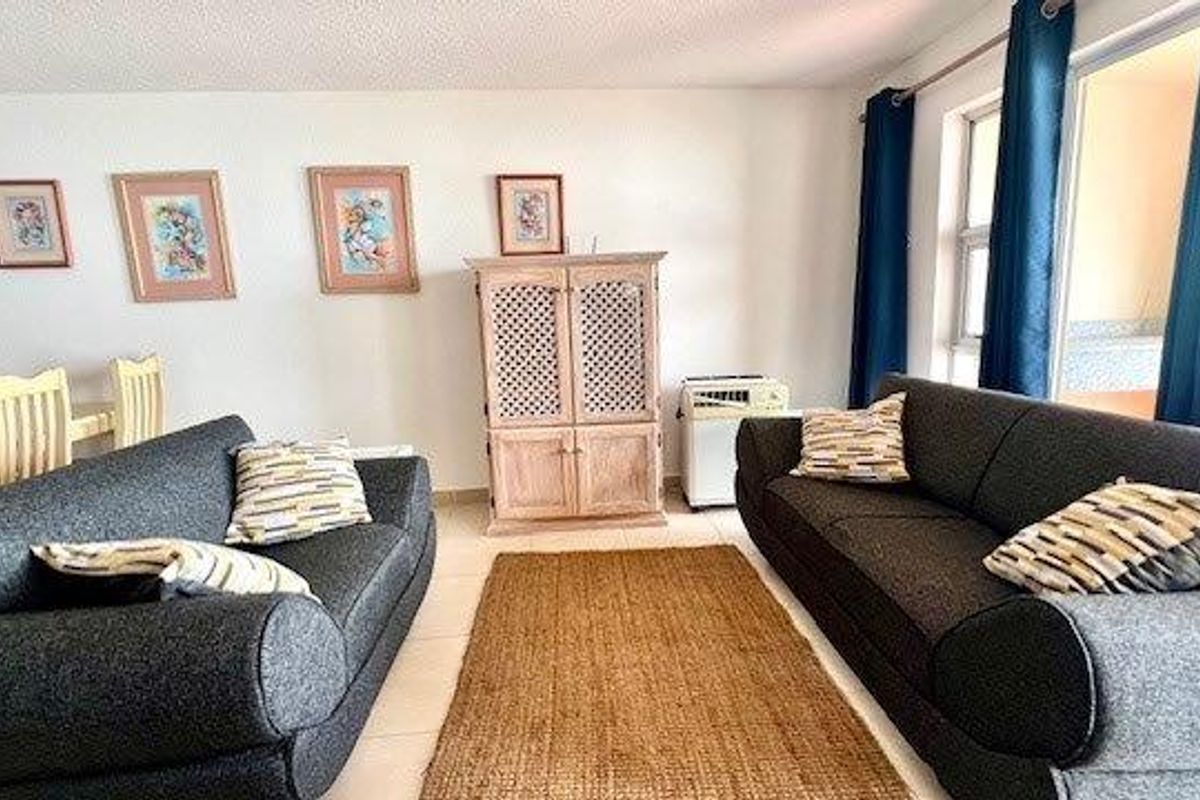 A bright living room area featuring tiled flooring and a sliding glass door leading to an adjacent space.