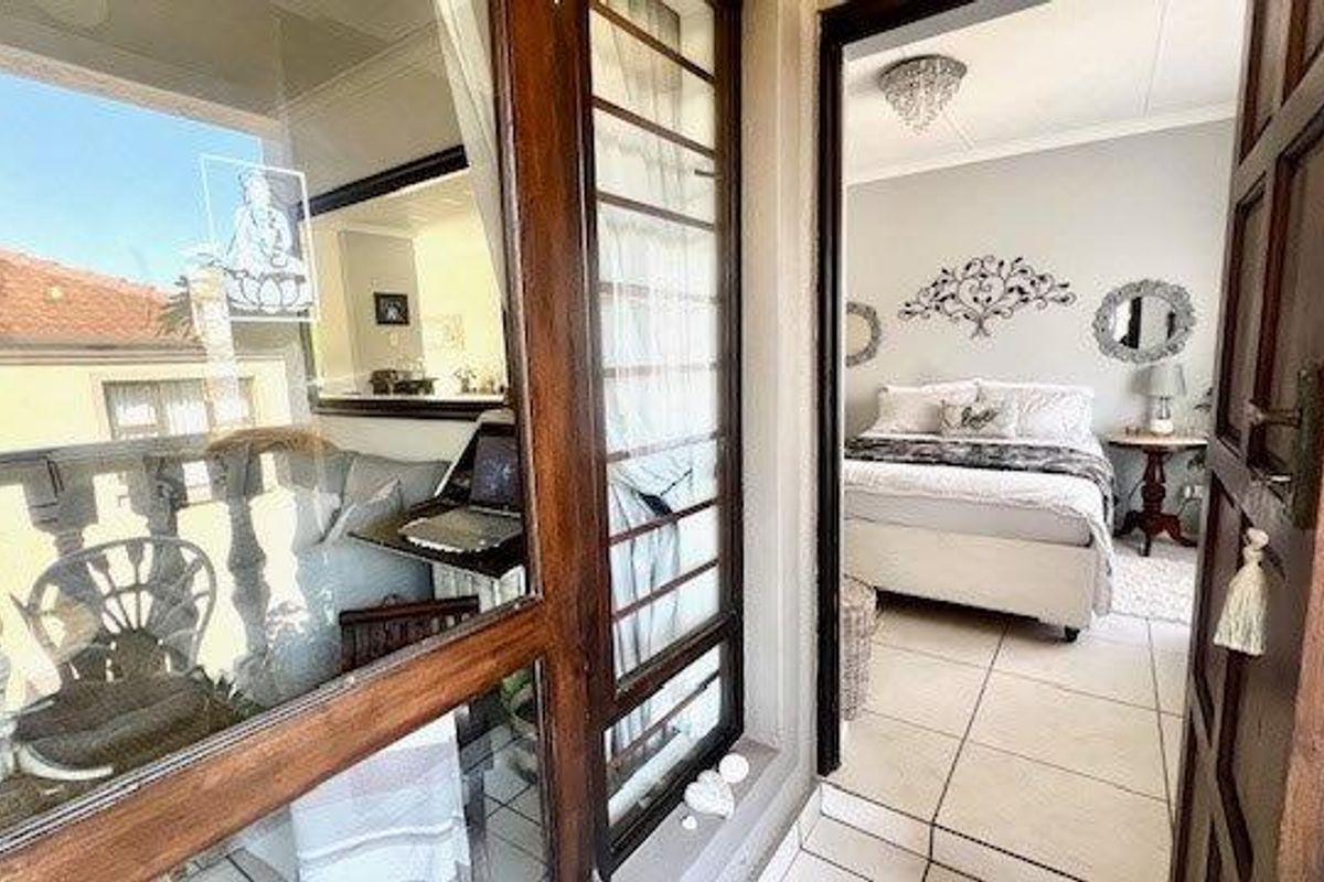 View from a balcony looking into a bedroom featuring tiled flooring and a wooden door frame.