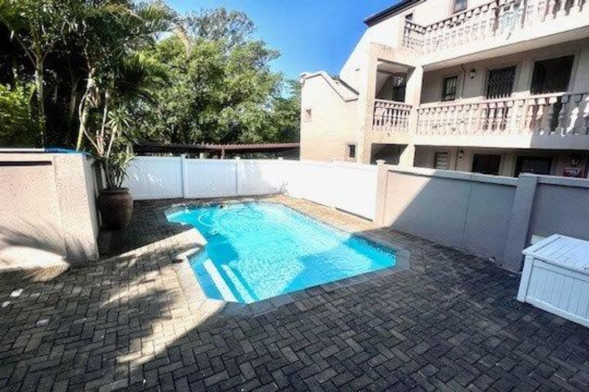 Communal swimming pool area featuring paved surround, perimeter walling, and direct access to the apartment building complex.