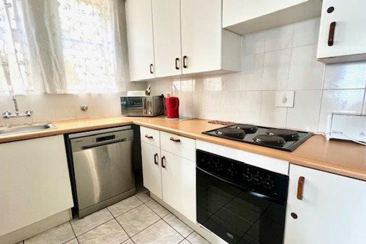 A functional kitchen featuring white cabinetry, laminate countertops, a tiled backsplash, and built-in electric cooking appliances.