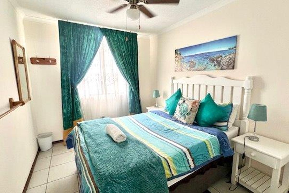 A functional bedroom featuring tiled flooring, a ceiling fan, and window treatments, offering a comfortable and well-lit space.