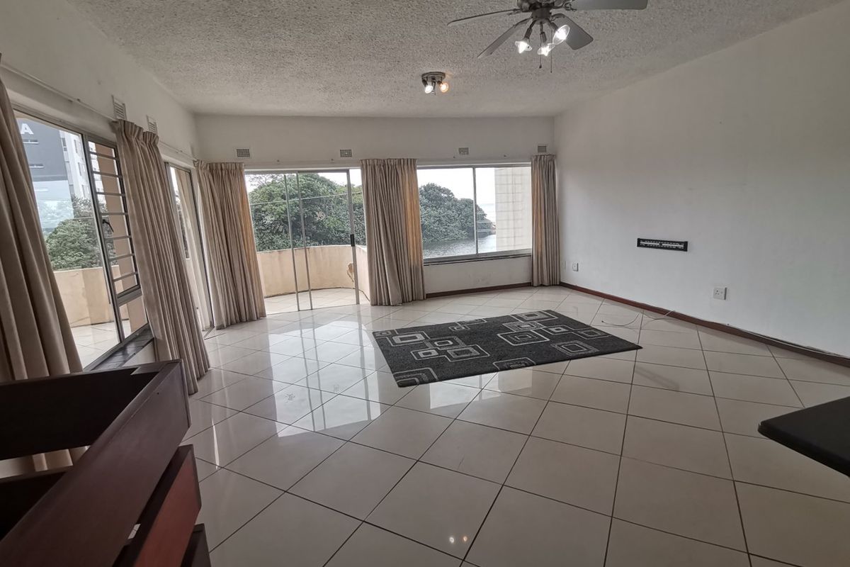 Spacious living area featuring large sliding glass doors, tiled flooring, and a ceiling fan, offering access to an outdoor balcony.