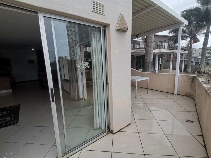 A covered patio area featuring tiled flooring and a sliding glass door providing access to the interior living space.