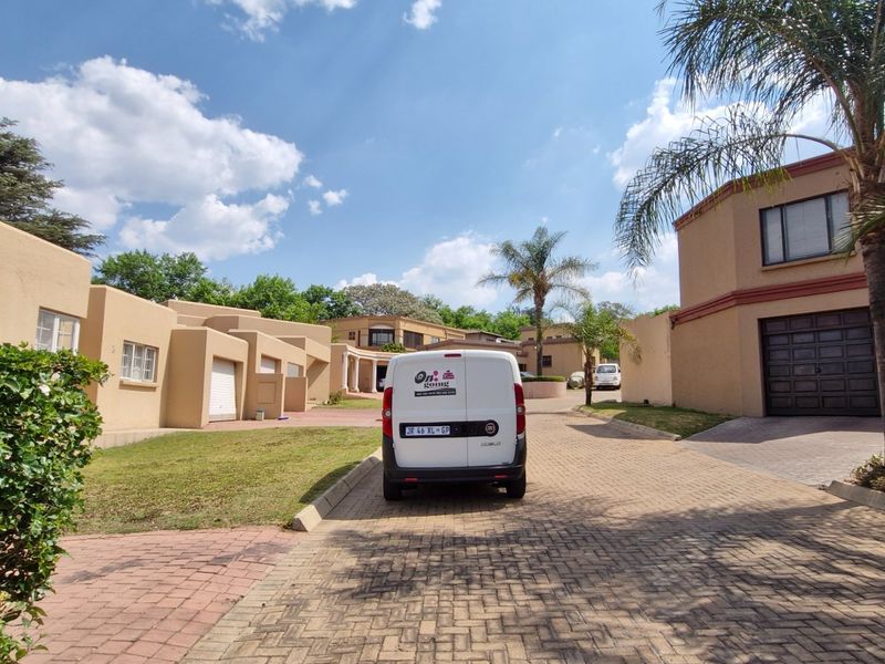 A view of the property's front exterior, featuring a paved driveway, multiple garage doors, and established landscaping.
