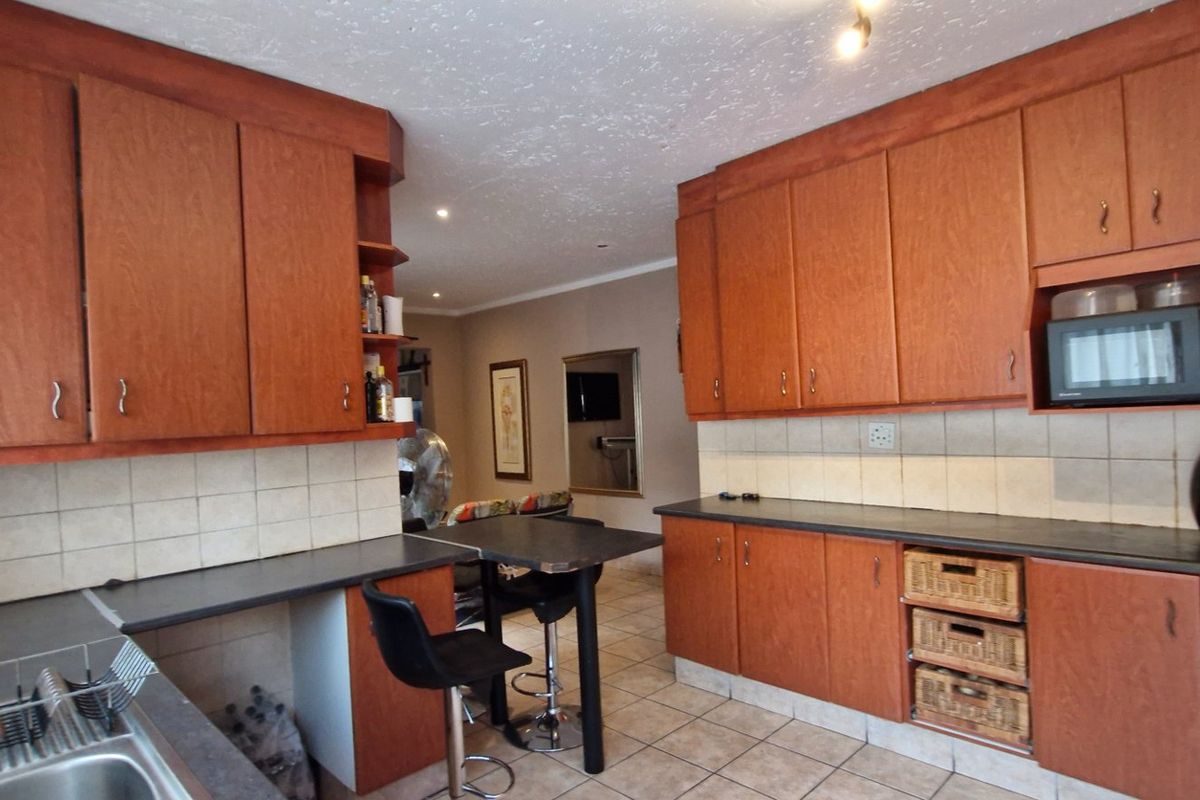 A functional kitchen featuring warm-toned wooden cabinetry, laminate countertops, a tiled backsplash, and integrated microwave, offering a classic and practical layout.