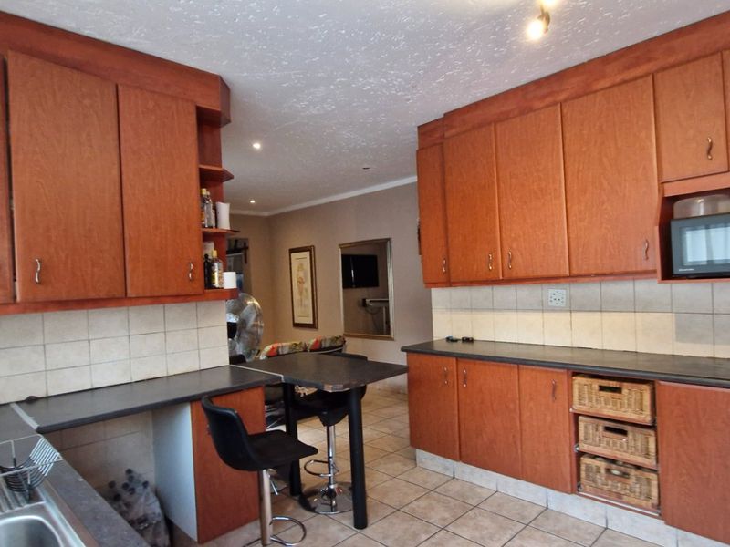 A functional kitchen featuring warm-toned wooden cabinetry, laminate countertops, a tiled backsplash, and integrated microwave, offering a classic and practical layout.