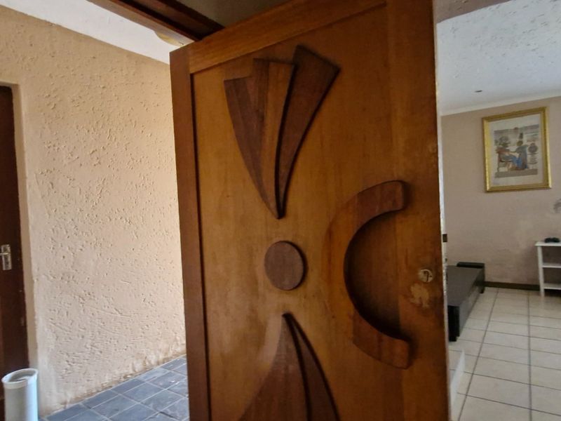 Entrance area featuring a decorative timber door, tiled flooring, and textured wall finishes leading into the main living space.