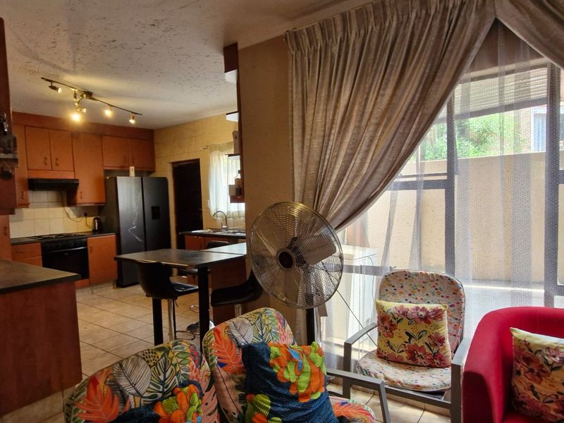 Open-plan living and kitchen area featuring tiled floors, built-in cabinetry, and a large sliding door providing access to the exterior.