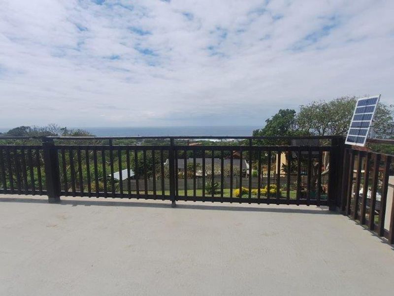 An elevated balcony featuring a timber balustrade and concrete flooring, offering expansive coastal views.