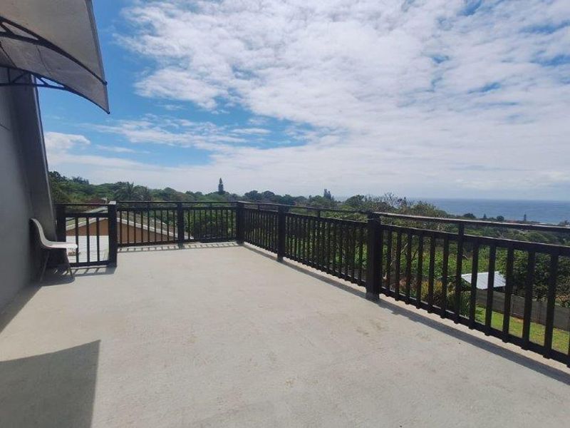 Spacious elevated balcony featuring a secure railing and expansive coastal views, providing an ideal outdoor space for relaxation.