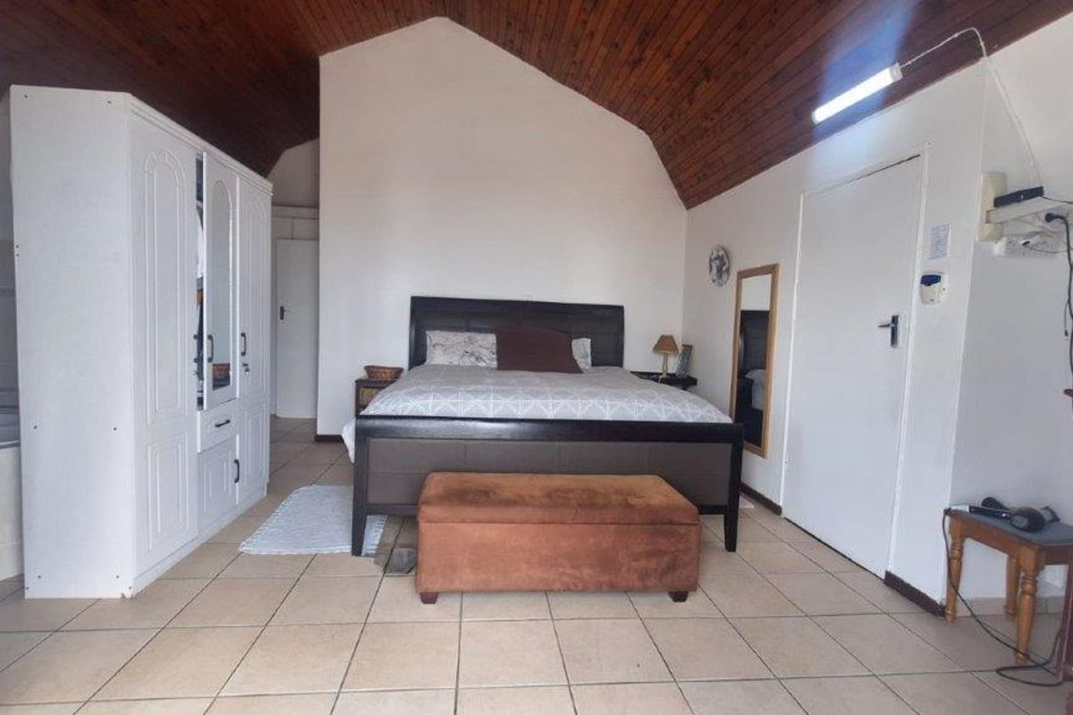 Spacious bedroom featuring a high vaulted timber ceiling and ceramic tiled flooring, offering a neutral canvas for potential interior updates.