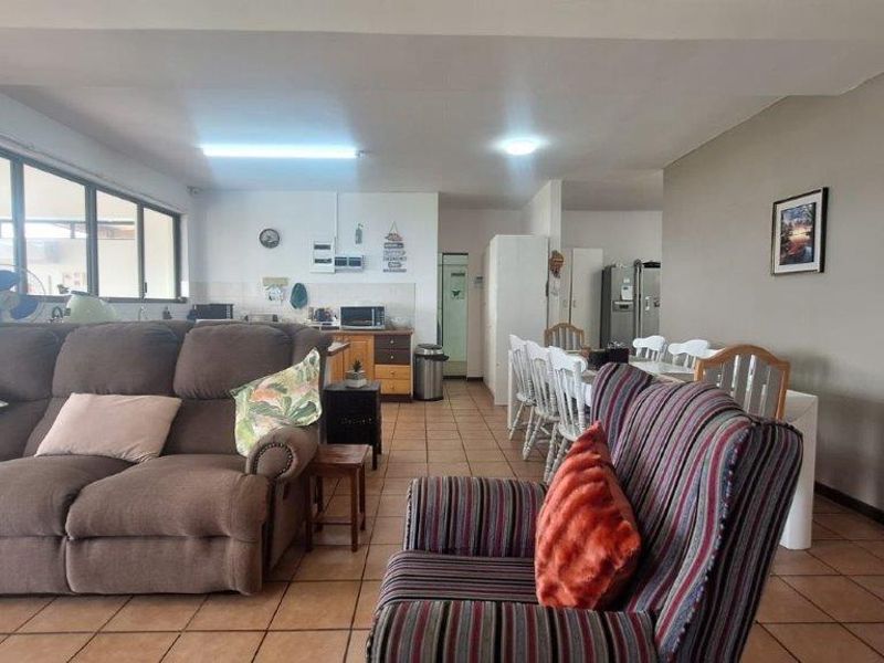 Open-plan living and dining area featuring tiled flooring and an integrated kitchen space with functional cabinetry.