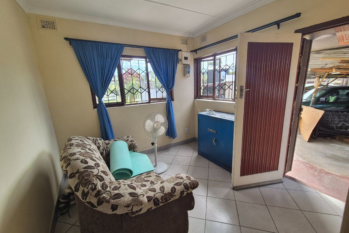 A small living area featuring tiled flooring, security bars on the windows, and direct access to an outdoor space.