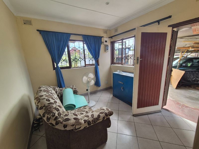 A small living area featuring tiled flooring, security bars on the windows, and direct access to an outdoor space.