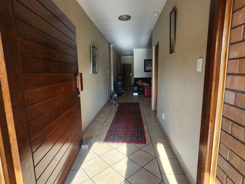 A welcoming entrance hallway featuring tiled flooring, a solid wood front door, and exposed brick accents leading into the home.