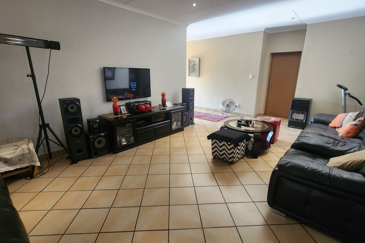 Spacious living room featuring neutral walls and durable ceramic floor tiles, providing a versatile area for relaxation and entertainment.