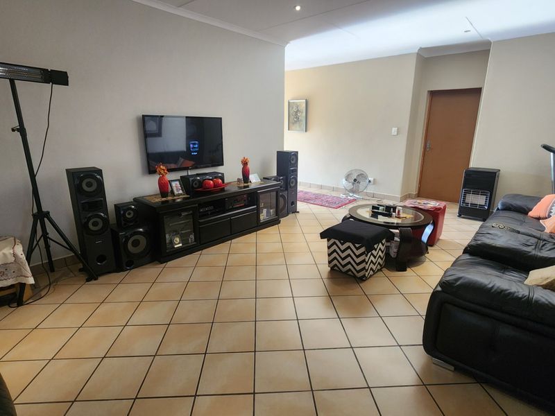 Spacious living room featuring neutral walls and durable ceramic floor tiles, providing a versatile area for relaxation and entertainment.