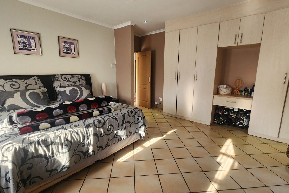 Spacious bedroom featuring neutral tiled flooring, ample built-in cupboard storage, and recessed ceiling lighting.