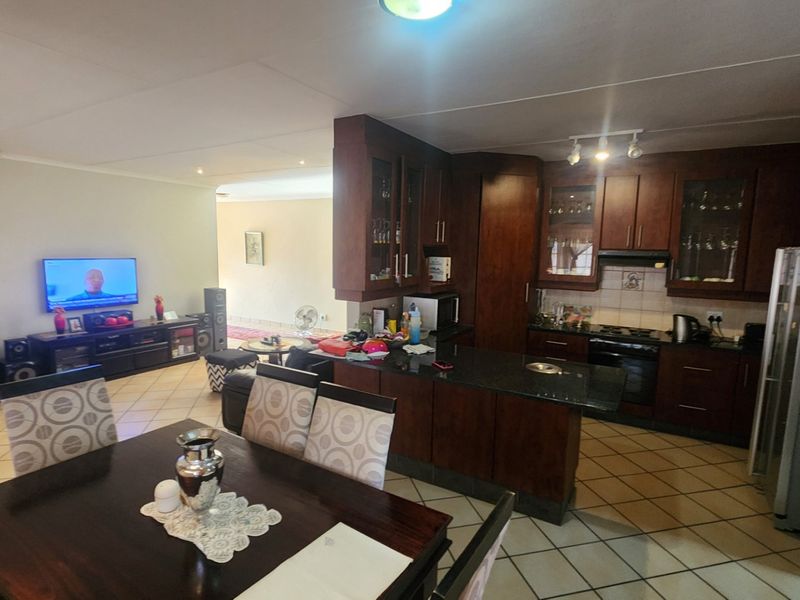 Open-plan living and kitchen area featuring dark wood cabinetry, granite countertops, and tiled flooring, creating a functional and connected family space.