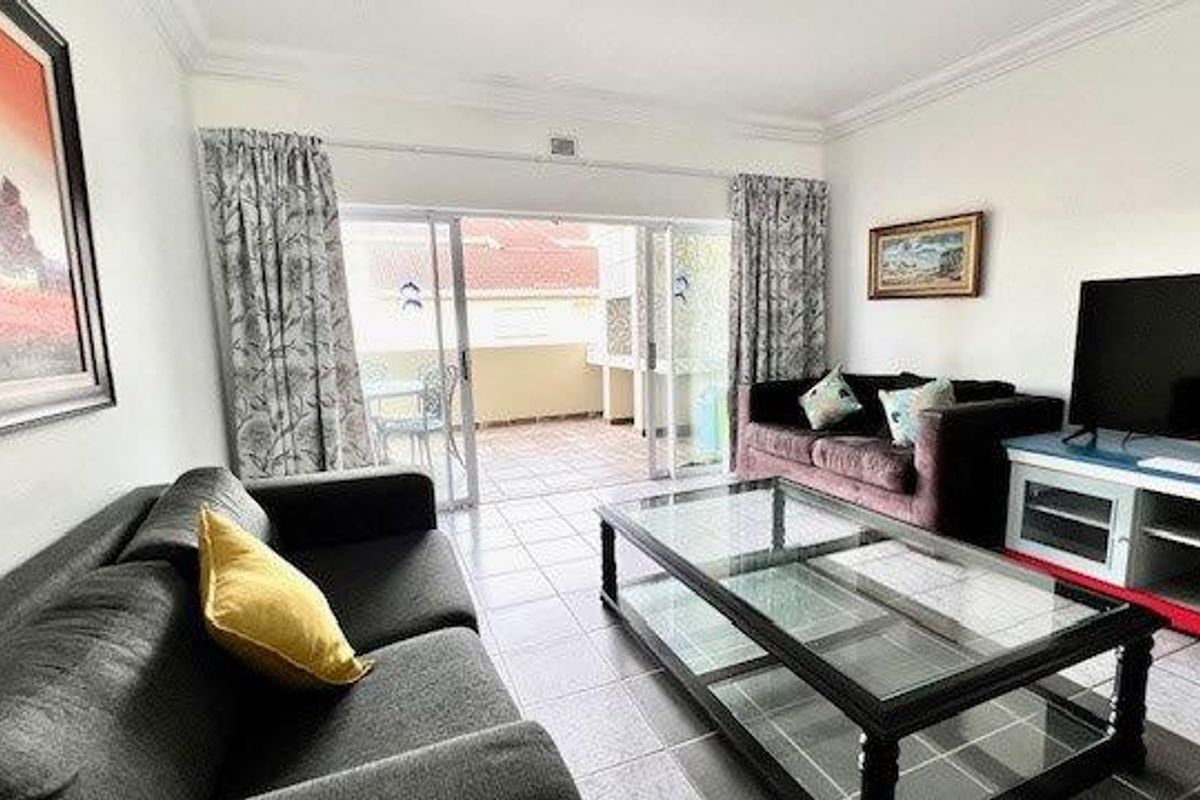 A bright living room featuring tiled flooring and large sliding glass doors that provide direct access to an outdoor patio area.