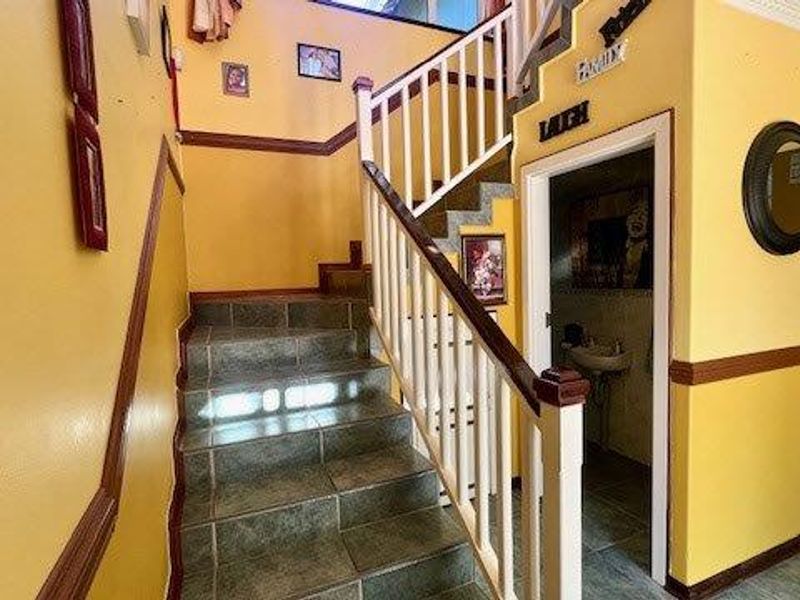 Entryway featuring a tiled staircase with a wooden balustrade, accented by chair rail and crown molding in a traditional yellow color scheme.