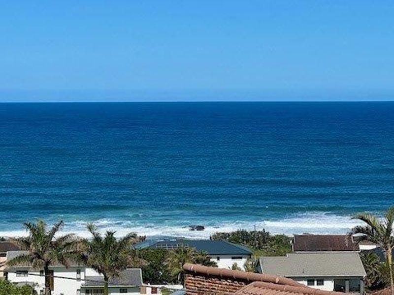A clear, elevated view of the ocean and coastline, showcasing the property's prime coastal location and surrounding residential neighborhood.