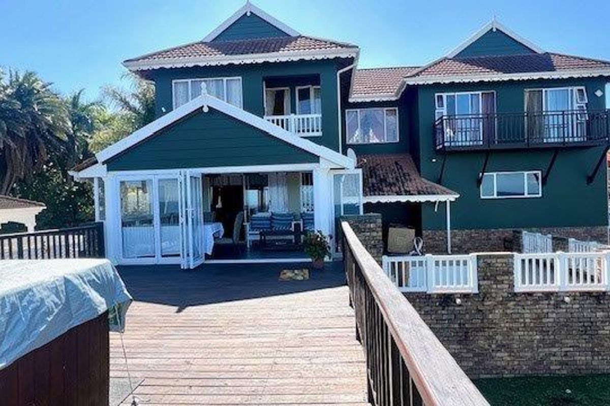 Rear view of a multi-story house featuring a large timber deck, balcony, and bi-fold doors leading into the living area.