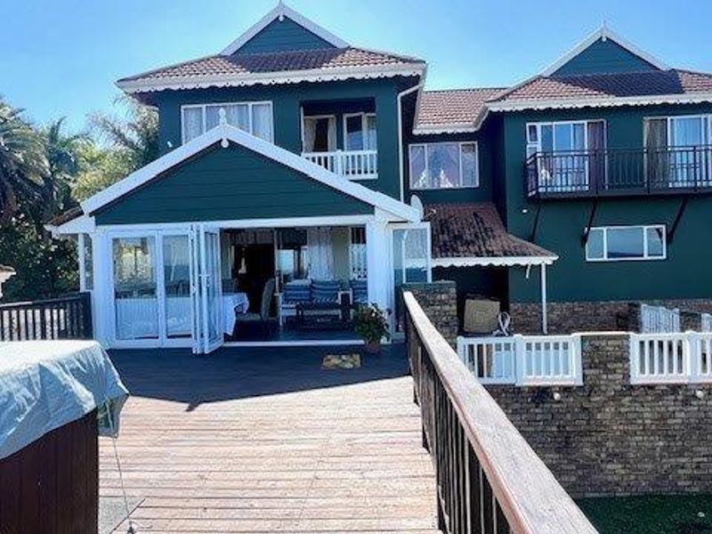 Rear view of a multi-story house featuring a large timber deck, balcony, and bi-fold doors leading into the living area.