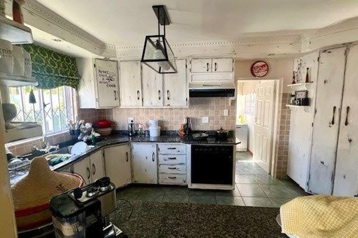 A functional kitchen featuring granite countertops, built-in cabinetry, integrated oven, and tiled flooring, offering a classic layout with potential for cosmetic updates.