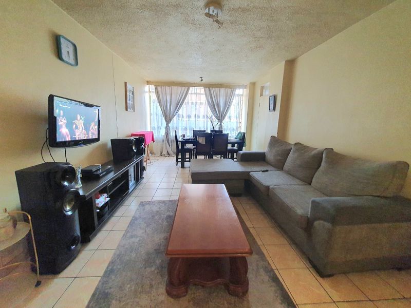 Open plan living and dining area featuring ceramic floor tiles and a textured ceiling, providing a functional space for relaxation and meals.