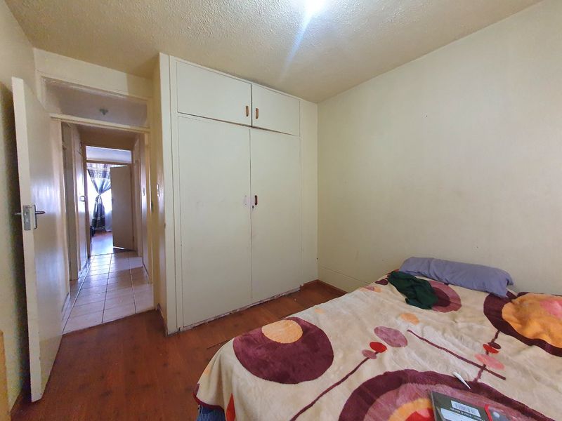 A bedroom featuring built-in wardrobes and laminate flooring, providing a functional space with potential for cosmetic updates to enhance its appeal.