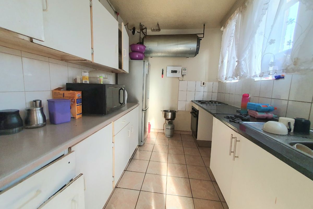 A functional galley-style kitchen featuring white cabinetry, tiled flooring, and a built-in oven, offering potential for modernization and aesthetic updates.
