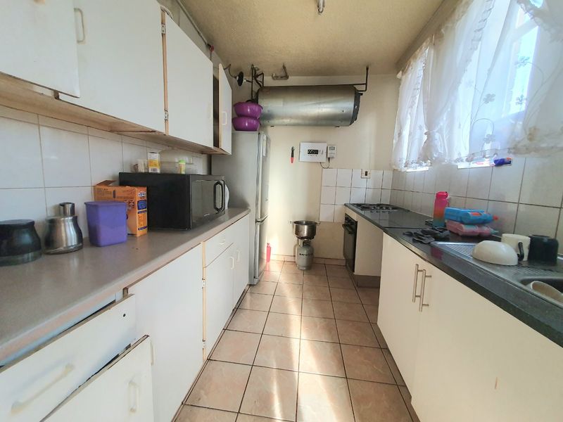 A functional galley-style kitchen featuring white cabinetry, tiled flooring, and a built-in oven, offering potential for modernization and aesthetic updates.