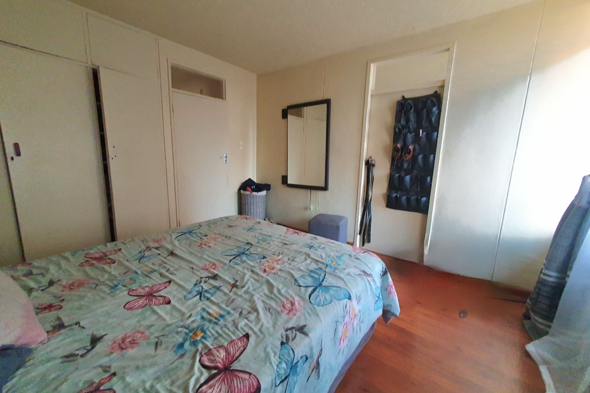 A bedroom featuring built-in cupboards and laminate flooring, offering a functional space with potential for cosmetic updates.