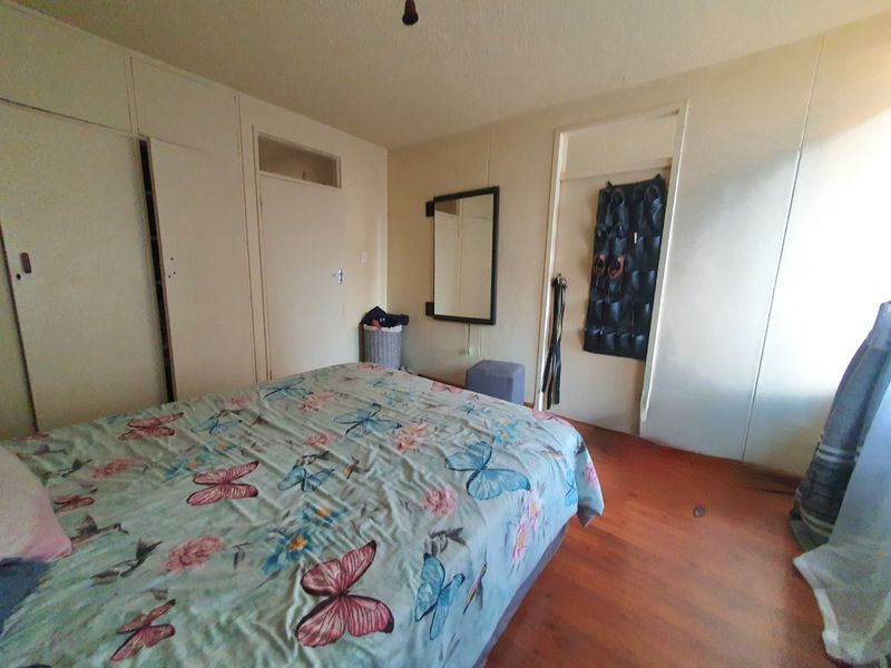 A bedroom featuring built-in cupboards and laminate flooring, offering a functional space with potential for cosmetic updates.
