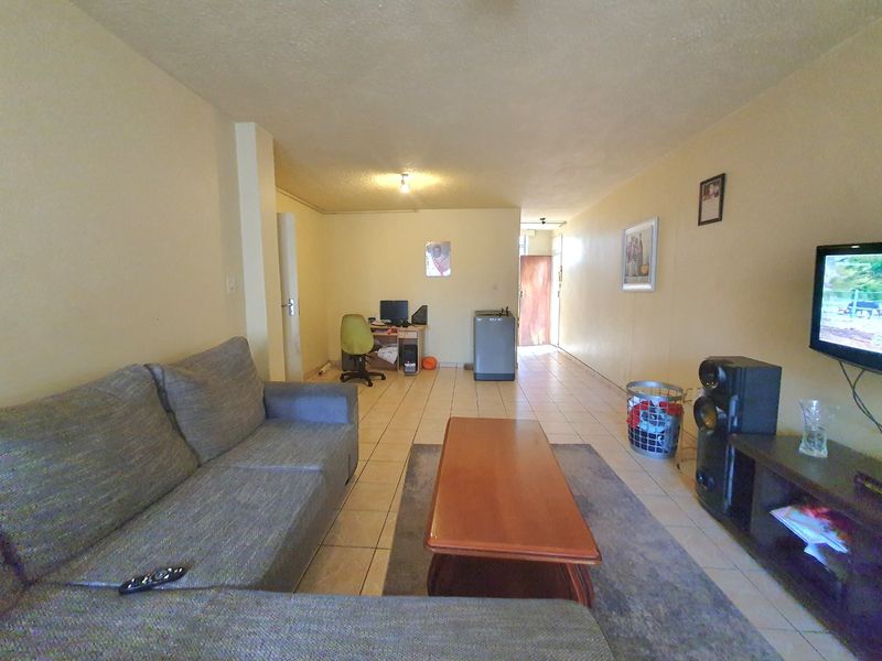 A spacious open-plan living area featuring neutral wall finishes and tiled flooring throughout, providing a versatile layout for comfortable daily living.