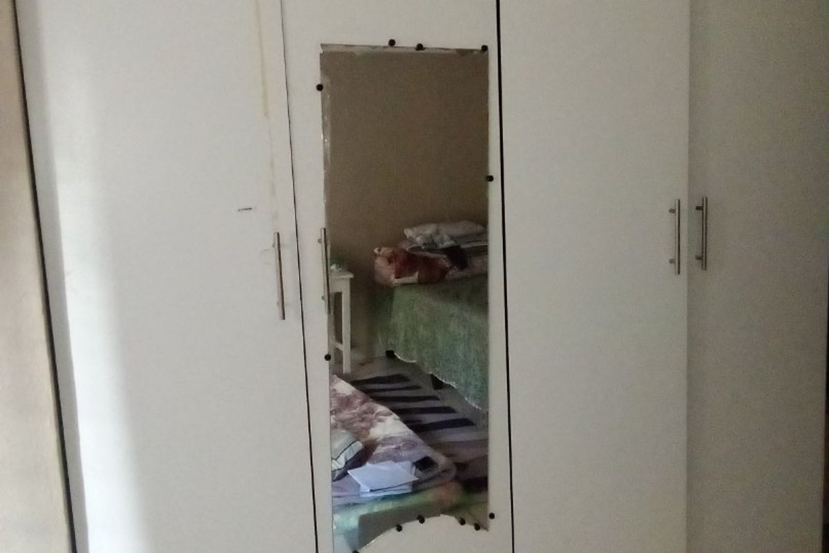 Bedroom featuring a built-in wardrobe with a damaged central mirror and tiled flooring.