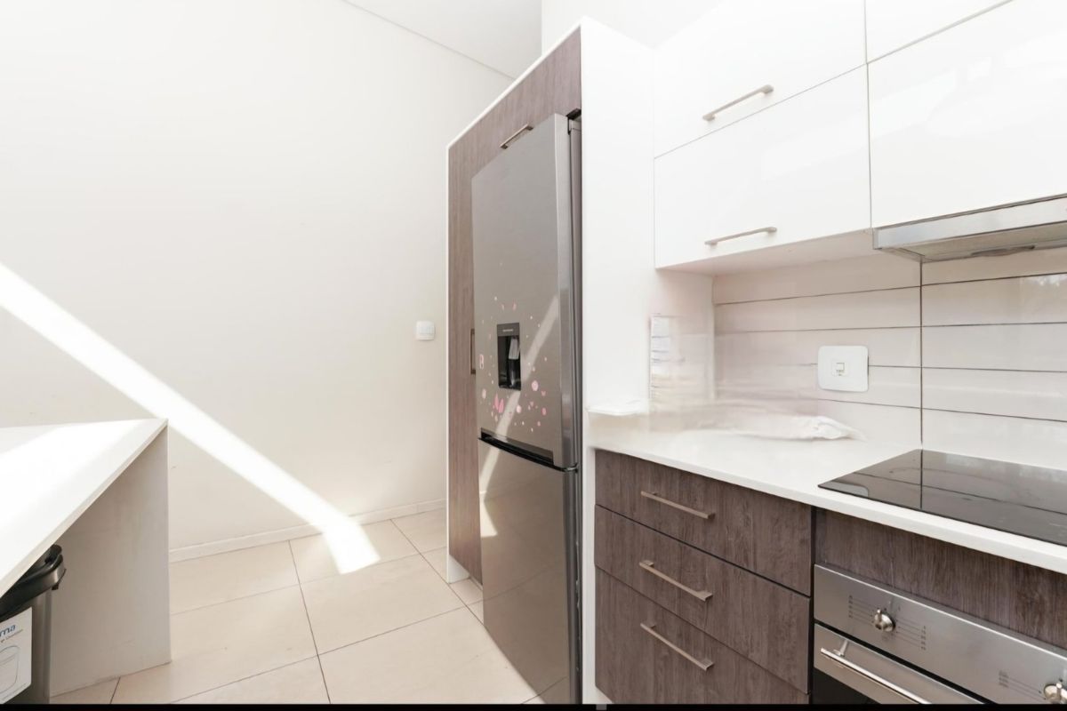 Modern kitchen featuring sleek two-tone cabinetry, stone countertops, integrated appliances, and tiled flooring with a clean, contemporary finish.
