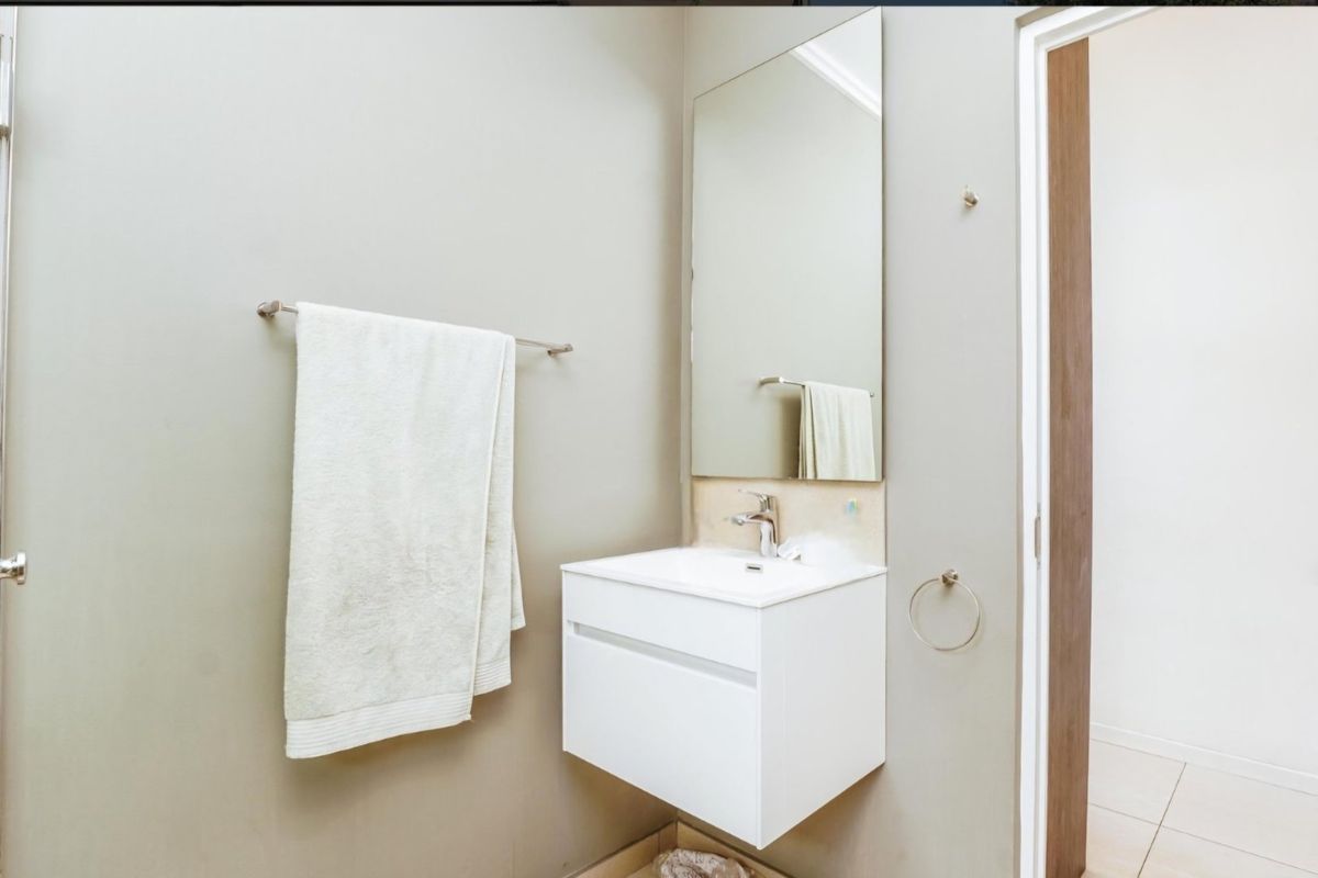 A clean and modern bathroom featuring a wall-mounted vanity with an integrated basin, chrome fixtures, and a large wall-mounted mirror.