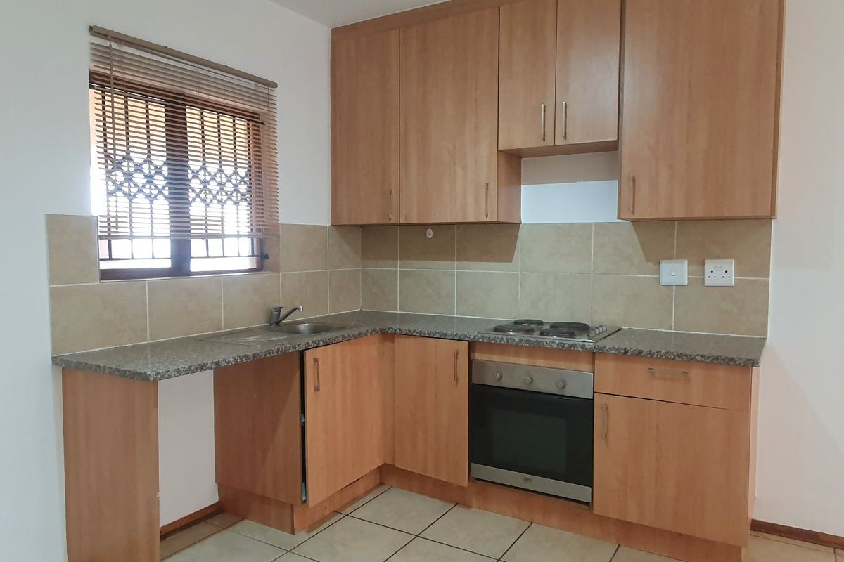 A functional kitchen featuring laminate cabinetry, granite countertops, a built-in oven, electric hob, and tiled backsplash with neutral floor tiles.