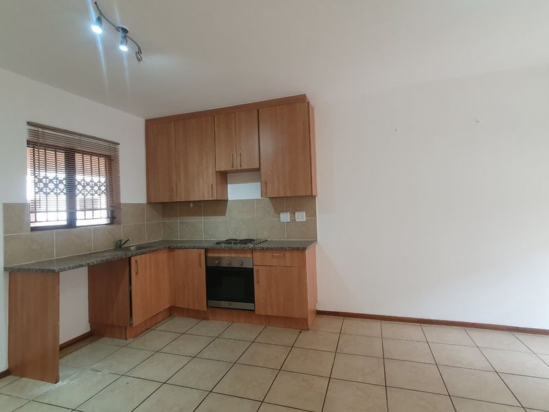 A functional kitchen featuring laminate cabinetry, granite countertops, built-in oven, gas hob, and tiled flooring. The space is currently vacant and ready for updates.