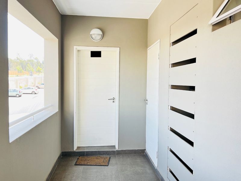 A clean and well-maintained apartment entrance foyer featuring tiled flooring, a bulkhead light, and secure access doors.