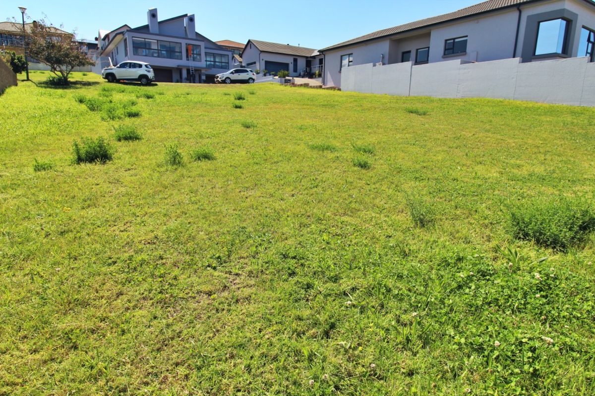 A vacant residential plot featuring a gentle slope, grass cover, and established boundary walls in a developed neighbourhood setting.