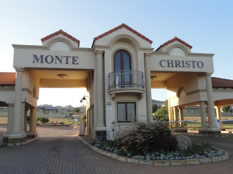 The main entrance gatehouse for Monte Christo estate, featuring a paved driveway, architectural columns, and a decorative balcony.