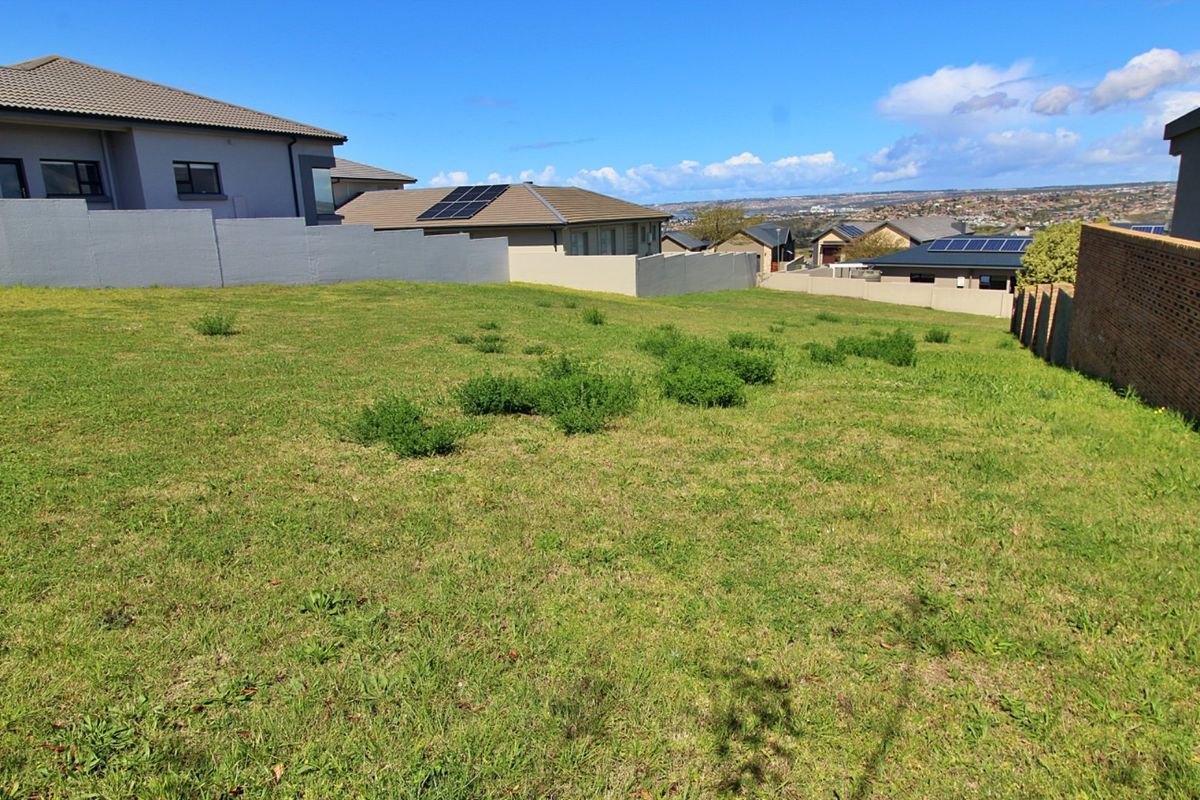 A vacant residential plot featuring a gentle slope, enclosed by boundary walls and situated within an established neighborhood.
