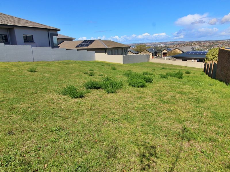 A vacant residential plot featuring a gentle slope, enclosed by boundary walls and situated within an established neighborhood.