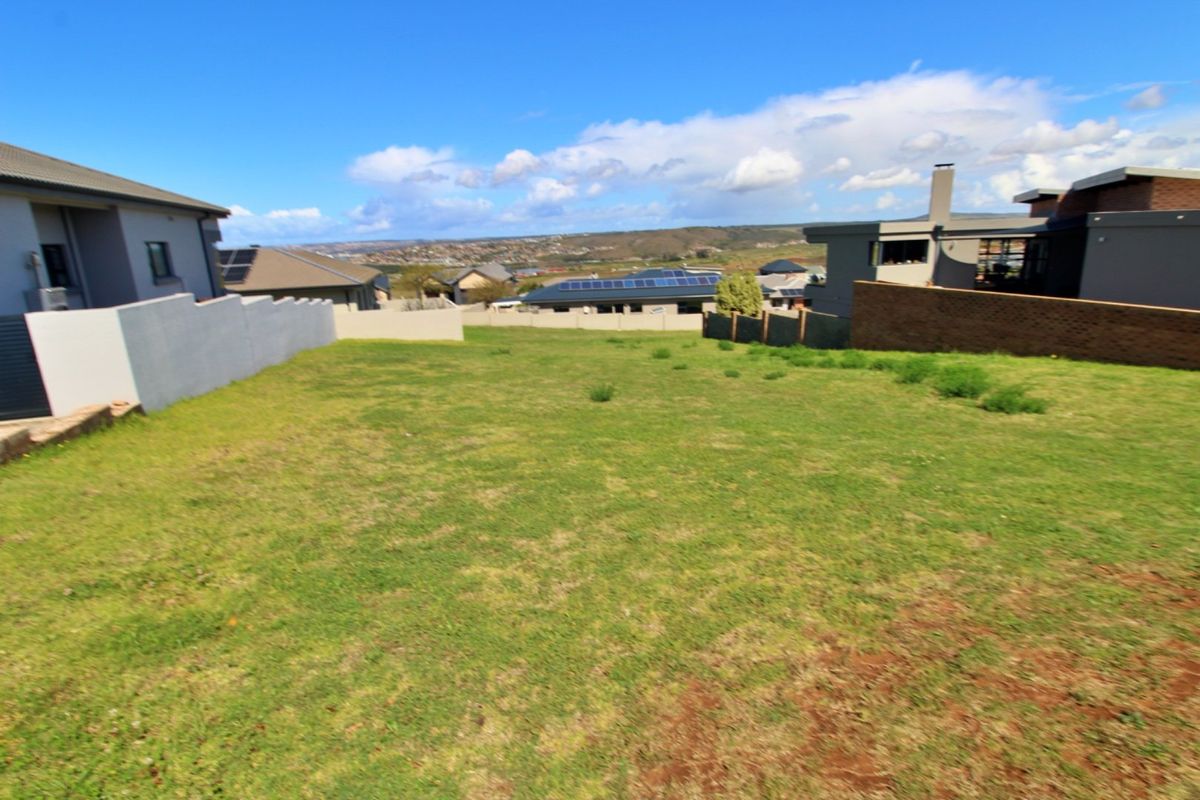 A vacant residential plot featuring a grassed area, enclosed by boundary walls and fencing, situated within a developed neighborhood.