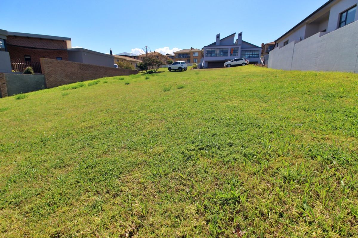 A vacant residential plot featuring a gentle slope, enclosed by boundary walls, situated in an established neighborhood.