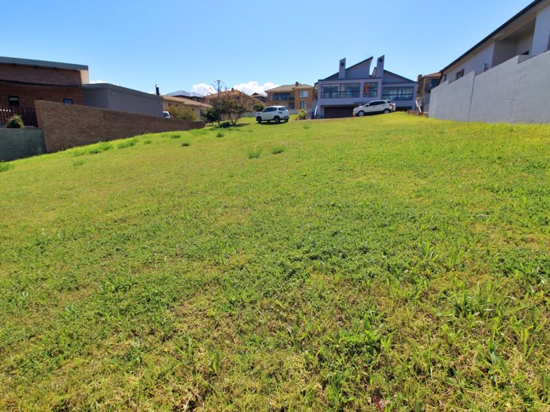 A vacant residential plot featuring a gentle slope, enclosed by boundary walls, situated in an established neighborhood.