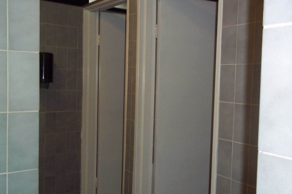 A commercial bathroom facility featuring tiled walls and multiple cubicle doors.